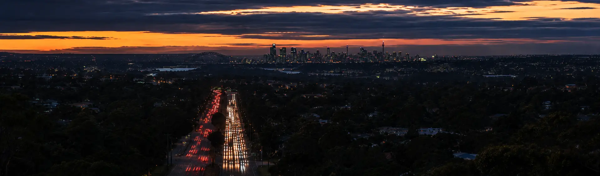 Dusk view over a Sydney arterial road with the city skyline on the horizon
